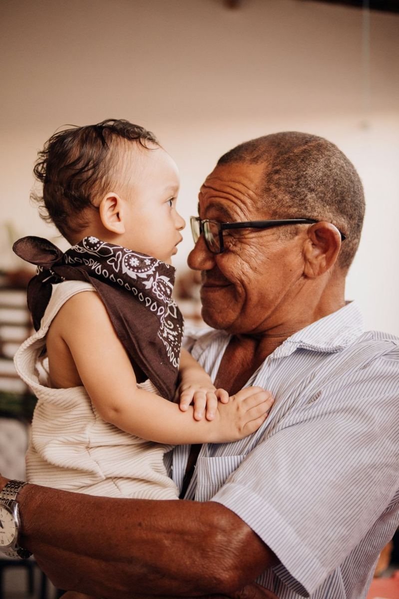 A grandfather smiling nose to nose with the baby he is holding.