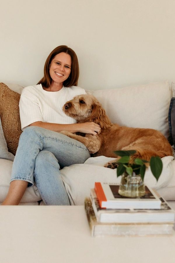 Shelley, smiling on her sofa at home with her dog.